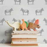 illustrated grey donkey on white background wallpaper pattern behind stack of books peel and stick